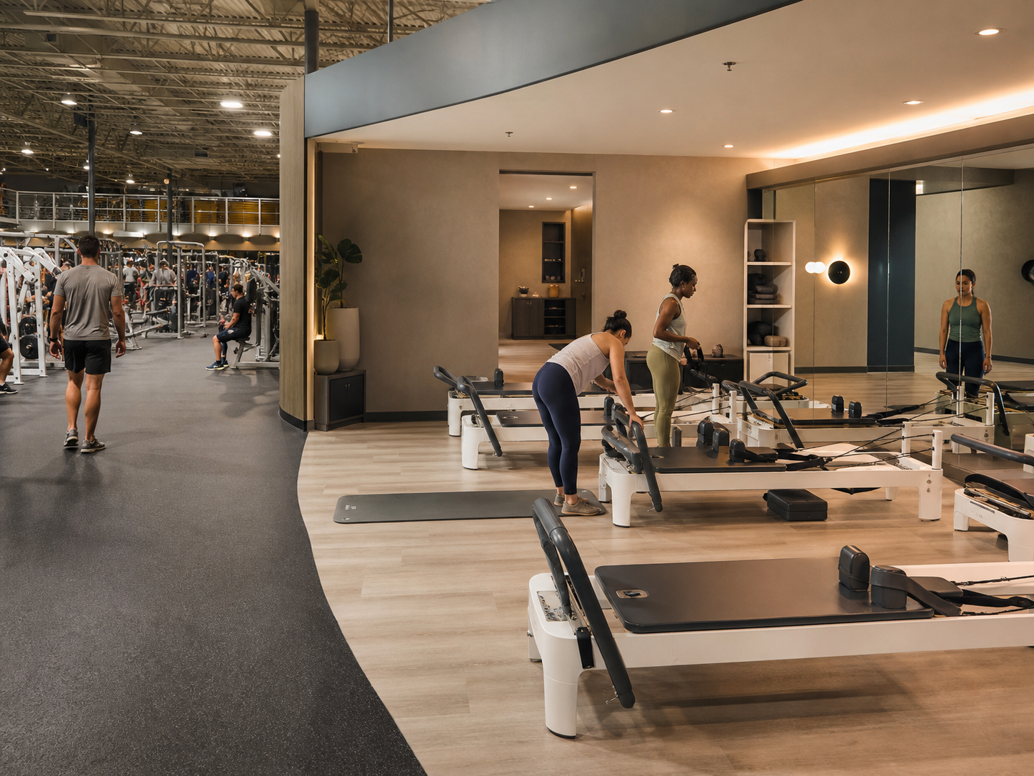 A calmer Pilates studio zone with reformers set beside the main gym floor