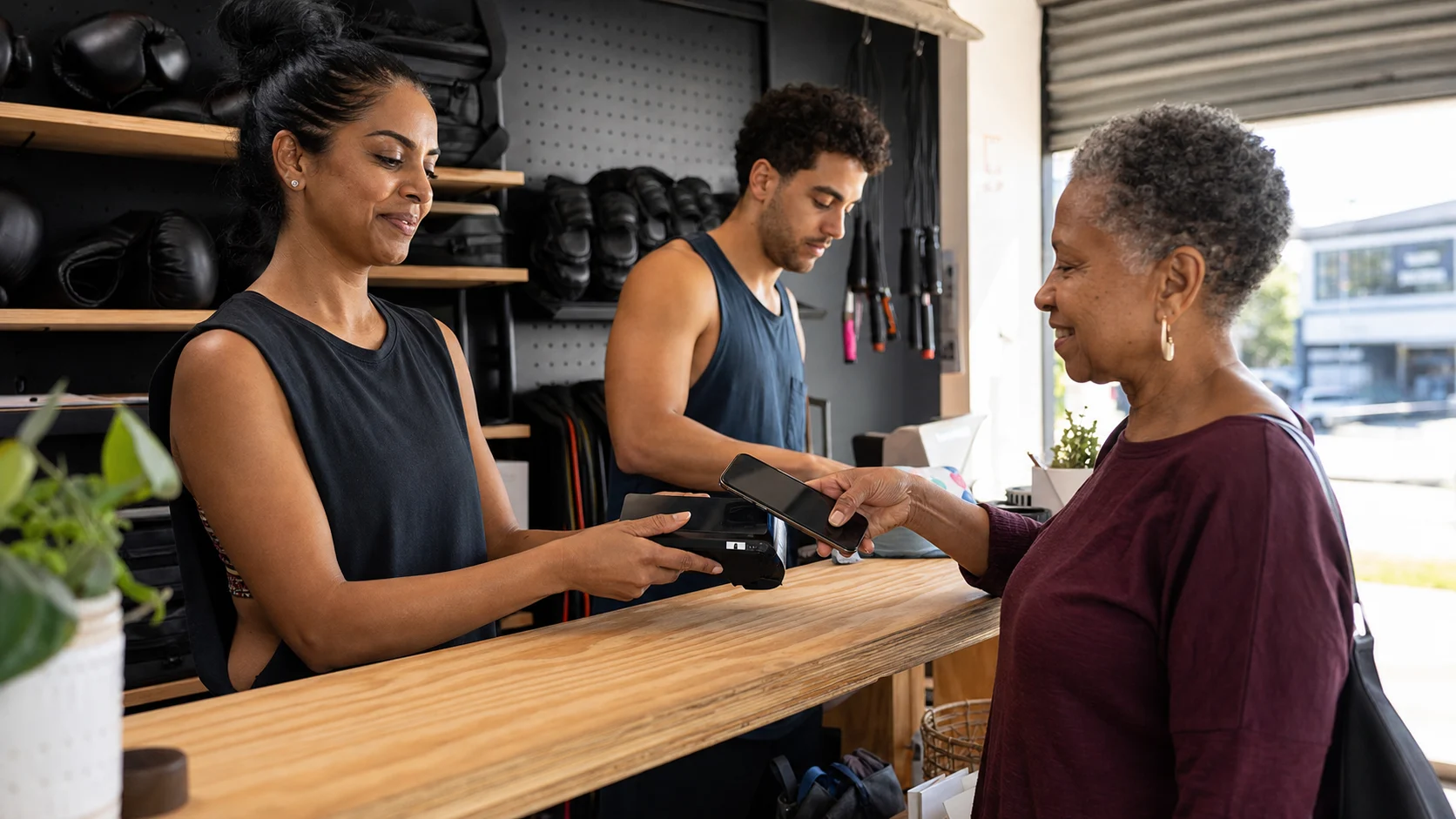 An older member tapping her phone on a card reader at an Australian boxing studio counter