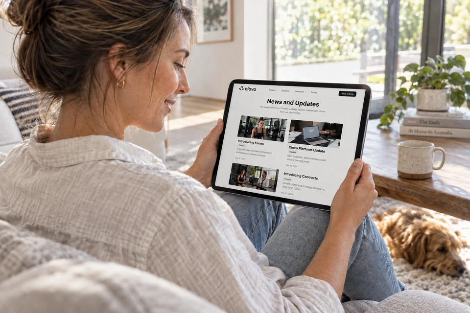 A woman relaxing at home while reading Clovo news and updates on an iPad.