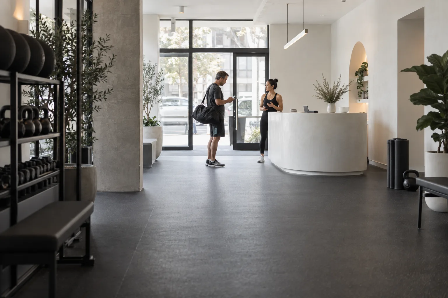 Studio instructor welcoming a client as he checks his phone at reception